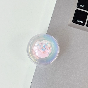 Macro shot of iridescent round phone grip with pink glitter accent on office desk