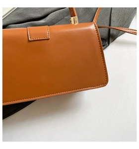 Nahaufnahme der braunen Ledertasche mit feinen Nähten und goldenen Metalldetails