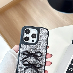 Hand holding iPhone case featuring chic woven texture and 3D black bow details