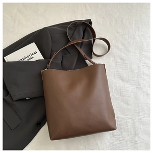Flat lay of brown leather tote bag with gold hardware next to a stylish blazer