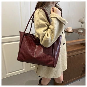 Detail of burgundy crocodile pattern tote bag with vintage leather texture and side profile