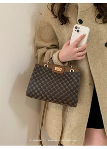 Detailed view of women's vintage satchel with brown pattern and golden clasp lock