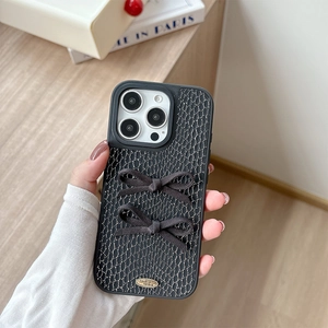Detail of black snake pattern iPhone case with 3D bows and engraved gold metal plate