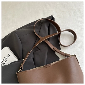 Detail of brown litchi pattern faux leather shoulder bag with adjustable strap and metal buckle