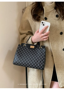 Model holding a retro black checkered handbag with a gold twist lock and a top handle