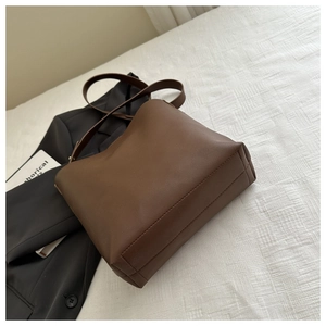 Detailed close-up of brown leather shoulder bag on white textured fabric background