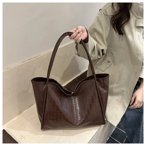 Detail view of brown faux crocodile embossed tote bag with slim shoulder straps