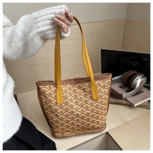 Chic tote bag with yellow leather handles and brown patterned canvas in a lifestyle setting