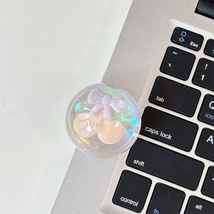 Detail of transparent bear phone grip with 3D cherry and bow on a laptop keyboard