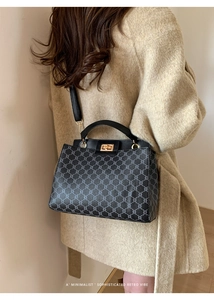 Detail of retro plaid pattern handbag with golden twist lock and leather handle