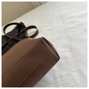 Detailed close-up of premium stitching and reinforced edges on dark brown leather bag