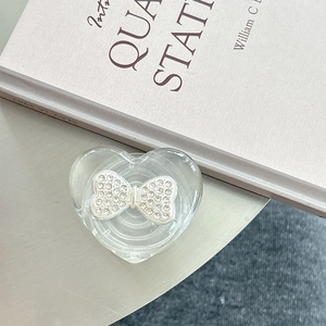 Macro shot of heart-shaped phone grip featuring a silver rhinestone bow on clear base