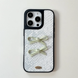 Detail of iPhone case with snakeskin texture, green fabric bows and gold love metal plaque