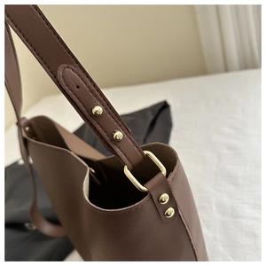 Detail of brown leather tote bag showing gold rivets and high-quality shoulder strap stitching