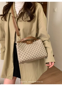Detailed close-up of retro monogram handbag with premium leather trim and gold metal buckle