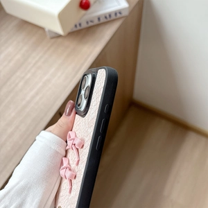 Close-up of pink snakeskin texture iPhone case featuring elegant satin bow decoration