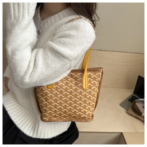 Detail of a mini tote bag with yellow geometric patterns held by a model in a cozy cafe