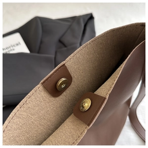 Detailed close-up of a brown leather shoulder bag with a secure magnetic snap closure