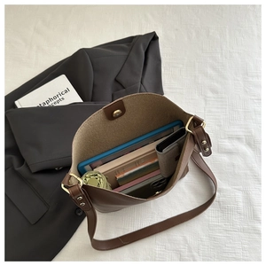 Deep brown textured leather bucket bag showing large interior space for books and a tablet