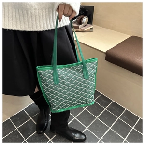 Close-up of green tote bag with Y-pattern canvas and matching leather handles
