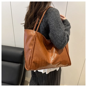 Detailed view of the brown crocodile texture and glossy finish on this large tote bag
