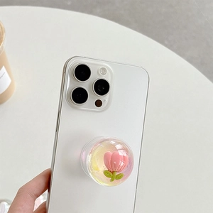 Pink tulip flower inside a crystal ball phone grip holder on a white smartphone