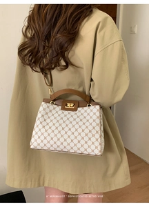 Close-up of a stylish cream canvas tote bag with brown leather accents and gold lock