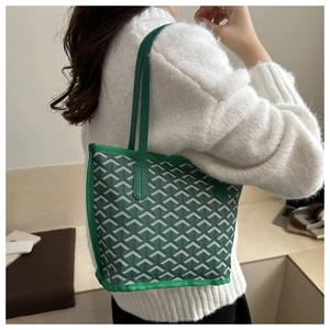 Detailed view of a green tote bag with interlocking Y-pattern on a model with white sweater