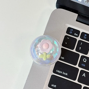 Detail of transparent floral acrylic phone grip with 3D pink flower on laptop keyboard