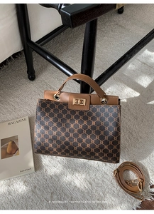 Macro shot of retro monogram handbag with metal twist lock and adjustable shoulder strap