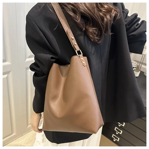 Brown matte leather bucket bag with adjustable strap and gold hardware on model