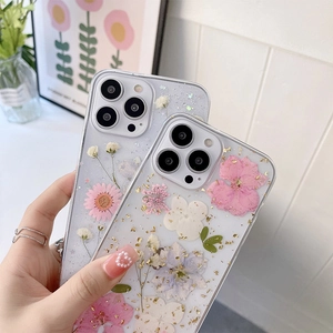 Détail de coque iPhone avec fleurs séchées, feuilles d'or et matériau TPU souple clair