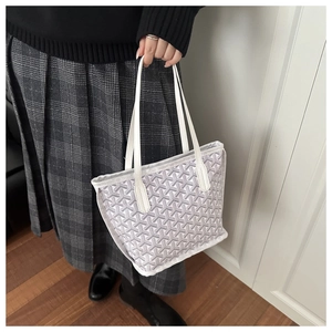 Detail of grey Y-shaped print tote bag with white leather handle held by a model