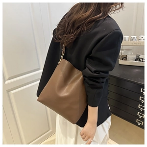 Detail showing the brown lychee grain PU tote bag size and texture on a model