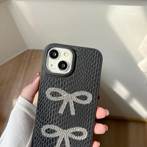Dettaglio della custodia iPhone in pelle nera con due fiocchi di strass lucidi