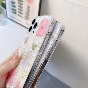 Détail d'une coque iPhone avec de vraies fleurs séchées roses et des éclats de feuille d'or