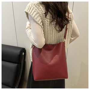 Side view of dark red matte leather bucket bag with metallic rivet detailing on strap