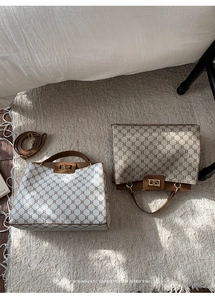 Close-up of retro monogram tote bags with leather handles and gold lock hardware