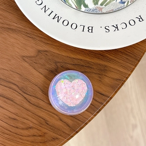 Detailed view of an iridescent purple phone socket grip featuring a pink glitter heart design