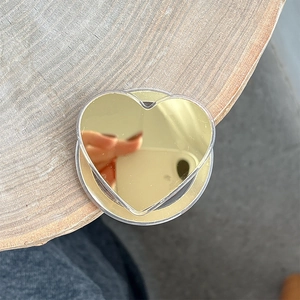 Detail view of heart-shaped gold mirror magnetic phone grip on natural wood surface