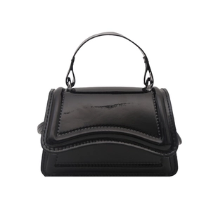 Minimalist black patent leather handbag with a wavy flap design and glossy mirror finish