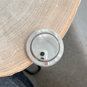 Close-up of a circular MagSafe mirror phone stand on a natural wood surface background