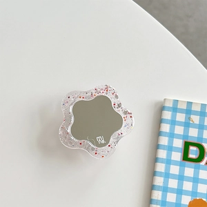 Detail of flower-shaped phone grip with round mirror and colorful glitter in acrylic