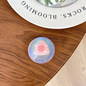 Close-up of holographic resin phone grip with 3D pink handbag decor on wooden desk