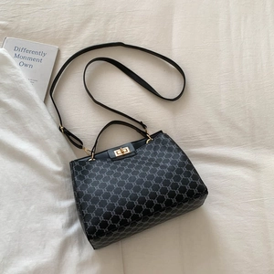 Chic black monogram handbag with gold twist lock and crossbody strap on fabric