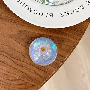 Detail of a floral holographic phone socket with purple petals and golden center