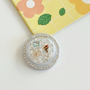 Detail of round ocean-themed phone grip with starfish, pearls, and rhinestones