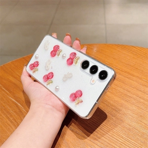 Detail of glittery white phone case with 3D cherry, pearl, and bow decorations