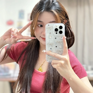 Détail de la coque iPhone pailletée avec nœud argenté 3D, perles et strass brillants