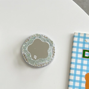 Detail of glitter flower phone grip with a mini mirror and rhinestones on a white desk